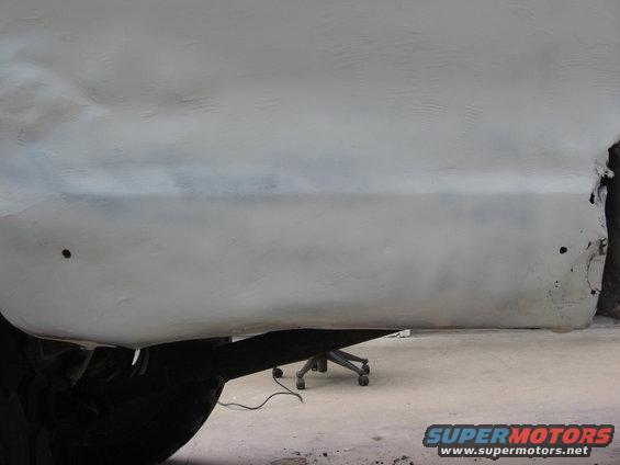 White 1979 Ford F-150 side panel with primer, showing rust damage on rear edge