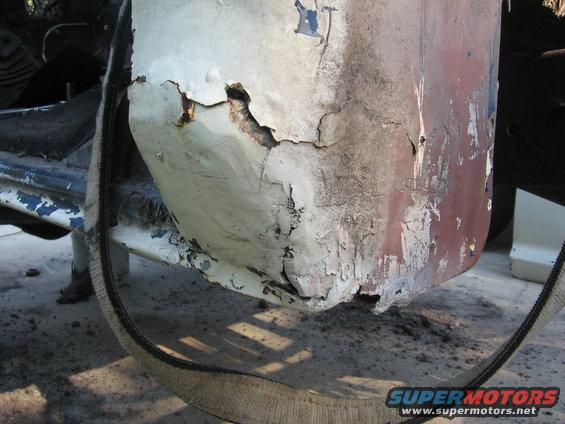 Heavily rusted fender and frame section with peeling paint and exposed metal