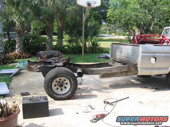 1979 Ford F-150 frame and bed disassembled, with tools on the ground
