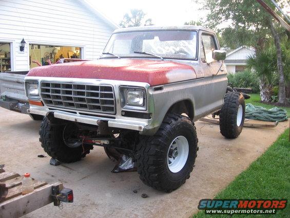 1979 Ford F-150 pickup truck with large tires, parked outside a garage