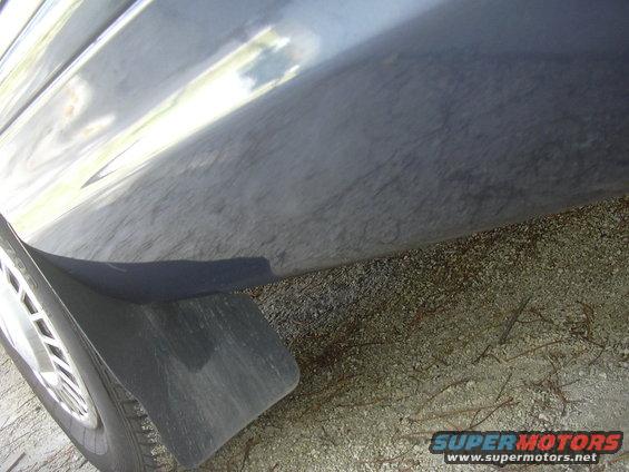 Close-up of a dark-colored vehicle's lower body panel and a black mud flap near the wheel