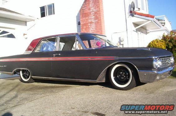 Black 1960 Ford sedan with red trim and whitewall tires, parked in driveway