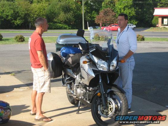 Suzuki V-Strom motorcycle parked with two men standing nearby. Luggage is attached to the rear
