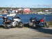 2003 Honda Shadow Aero - Two motorcycles are parked by a waterfront with buildings and boats in the background.