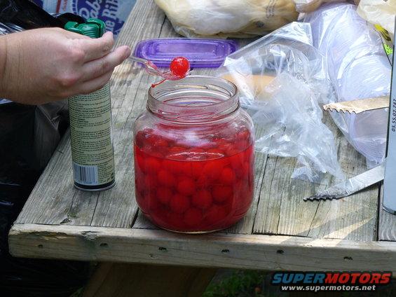 Jar of cherries on a wooden table with a can and plastic bags