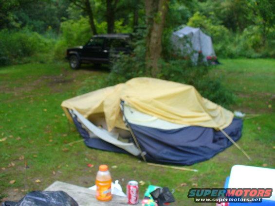 Black SUV parked in a campsite with tents
