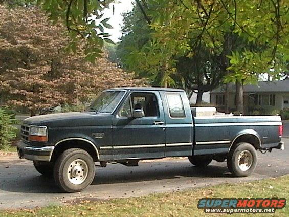 Dark green Ford F-250 pickup truck parked on a street, side view
