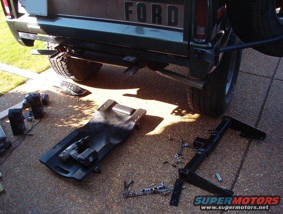 01bumperoff.jpg This is a JBG "kit" which comes with the receiver, 2 nut plates, 6 Gr.8 bolts/split washers/flat washers, and NO INSTRUCTIONS whatsoever.  After removing the rear bumper, I put the receiver against the frame forward against the tank strap, and found that the rear holes line up with some slotted holes in the frame.  So I marked the other 4 slots on the frame & fuel tank skidplate.  I removed the skidplate and drilled the 2 holes that hit it slightly inboard so that the skidplate would be pulled outward away from the tank later.