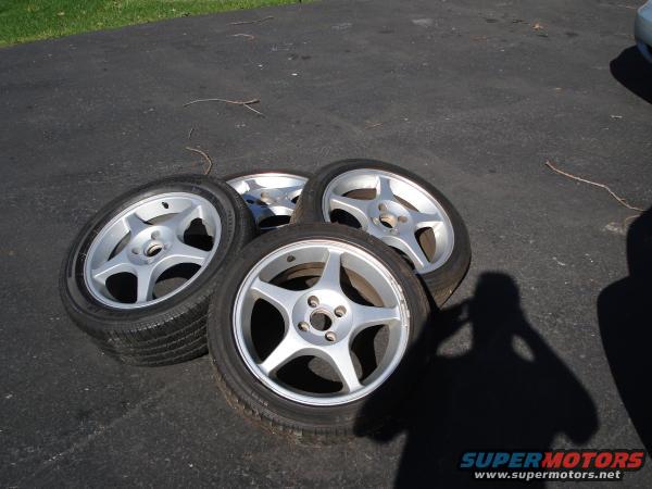 four alloy wheels with tires on asphalt