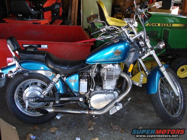 Blue motorcycle with chrome exhaust and black seat, parked indoors