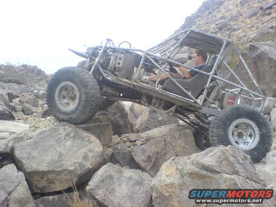 Custom off-road buggy with roll cage navigating rocky terrain