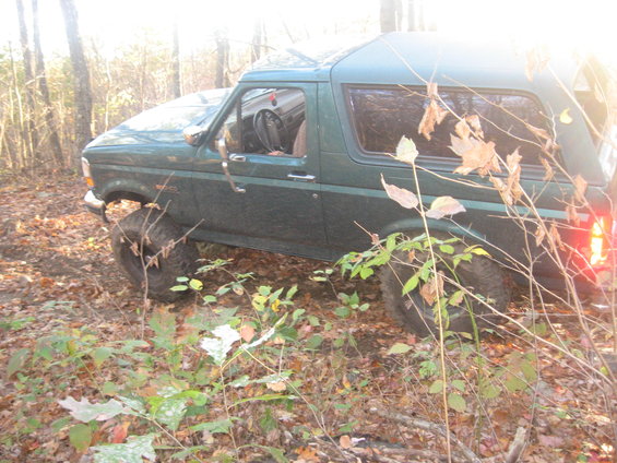 Green 1996 Ford Bronco off-roading in woods