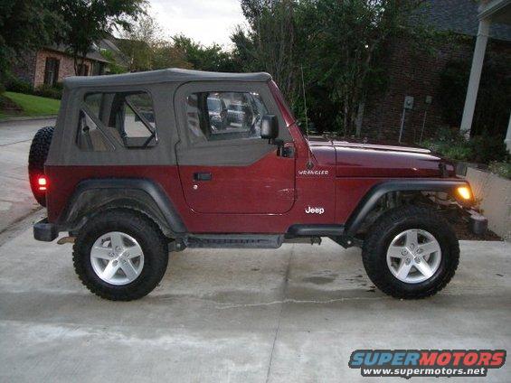 Red Jeep Wrangler with soft top parked on concrete driveway