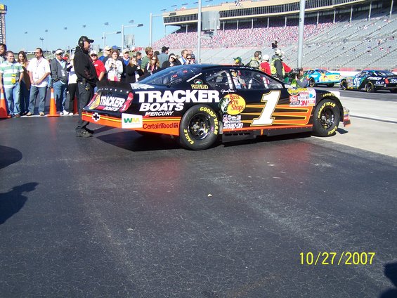 NASCAR race car with 'Tracker Boats' livery, number 1, on pit road with spectators and other cars in background. Date stamp 10/27/2007