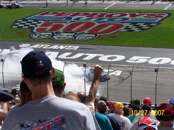 Race car doing a burnout on track with Pepboys Auto 500 logo in background