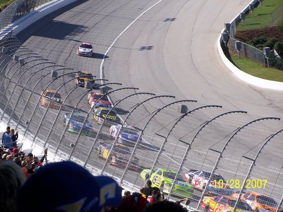 NASCAR race cars on a track, with spectators in the foreground. A date stamp reads 10/28/2007