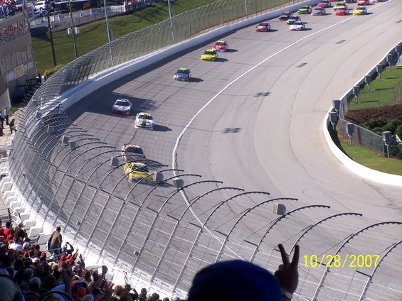 Stock cars racing on a track, with spectators in the foreground. Date stamp reads 10/28/2007