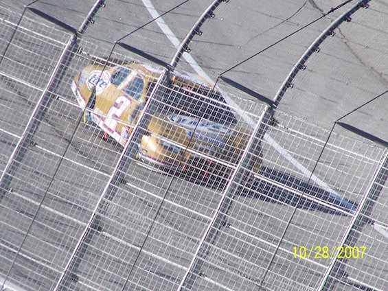 NASCAR race car with number 12 and 'Miller Lite' livery on a race track, seen through a fence. Date stamp reads 10/28/2007