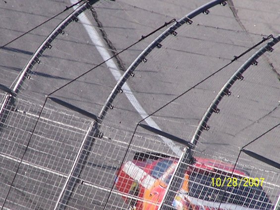 Race car on track, seen through a fence. Date stamp reads 10/28/2007