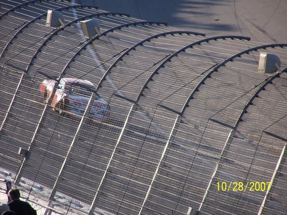 Race car on track, seen from above, with a fence in the foreground. Date stamp reads 10/28/2007