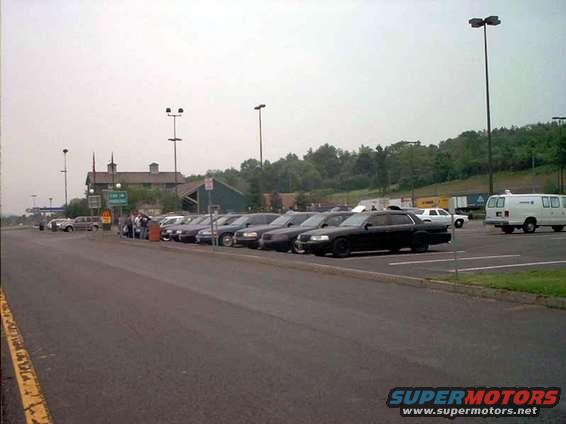 Cars parked in lot near a building with trees in background