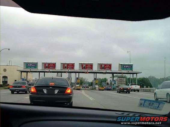 Black 2000 Ford Crown Victoria at a toll plaza, rear view. Brake lights are on