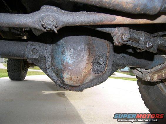 Underside view of a vehicle's rear axle differential, showing grease and some blue paint