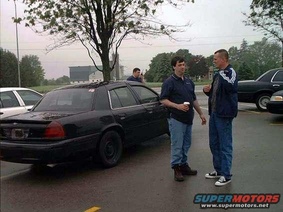 2000 Ford Crown Victoria parked on wet asphalt, two men standing nearby