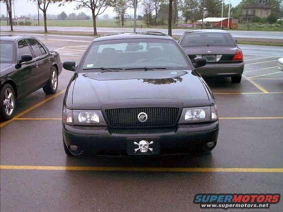 Black Mercury Grand Marquis with skull and crossbones plate parked next to another sedan
