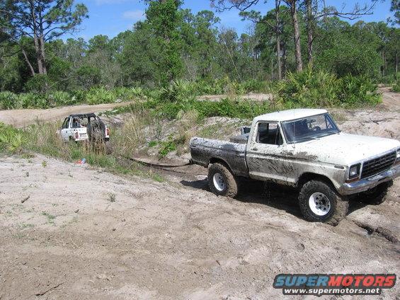 White 1979 Ford F-150 stuck in mud, being towed