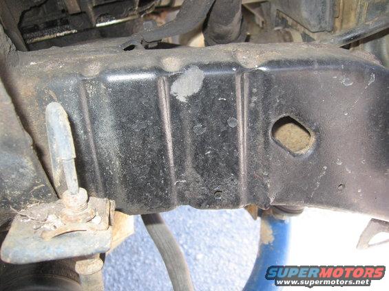 Close-up of a vehicle's frame rail with visible rust and damage