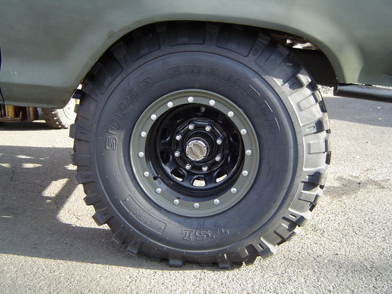 Close-up of a Super Swamper TSL off-road tire on a black wheel with grey trim
