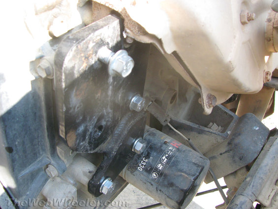 Black oil filter with "3330" text attached to engine block with metal bracket