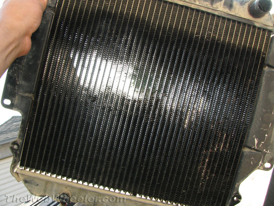 Radiator with black fins and metal frame, held by a hand