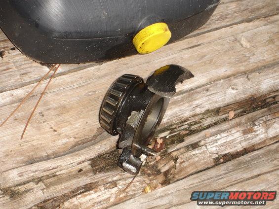 Broken wheel bearing assembly and oil drain pan on wooden surface