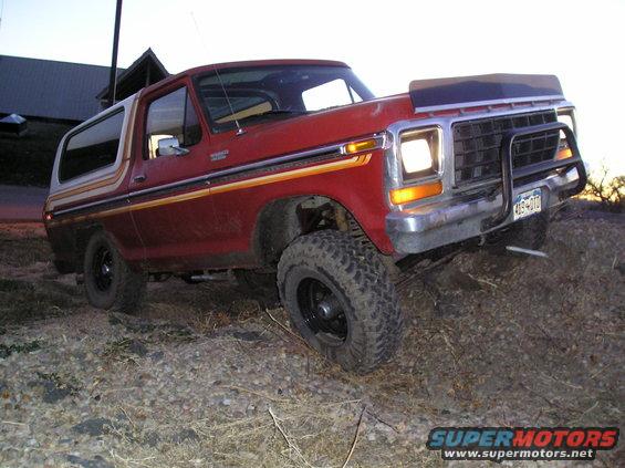 Red Ford Bronco with off-road tires driving on dirt and gravel