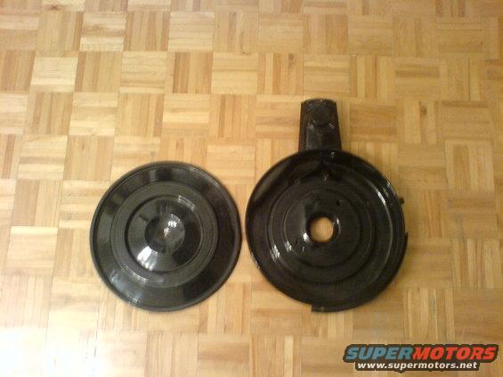 Two black air cleaner housings on a wood floor