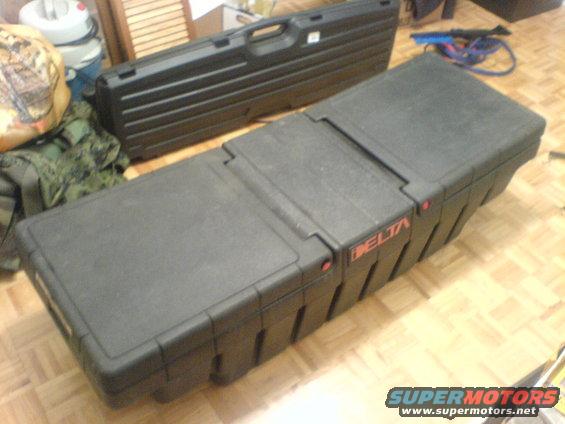 Two black Delta storage cases on a wood floor, one in the foreground, the other behind it