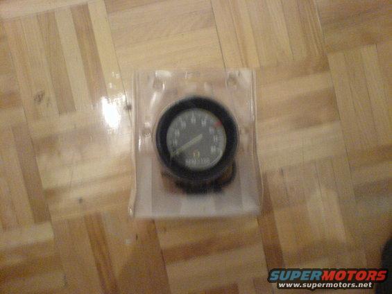 Tachometer gauge in plastic packaging on wood floor