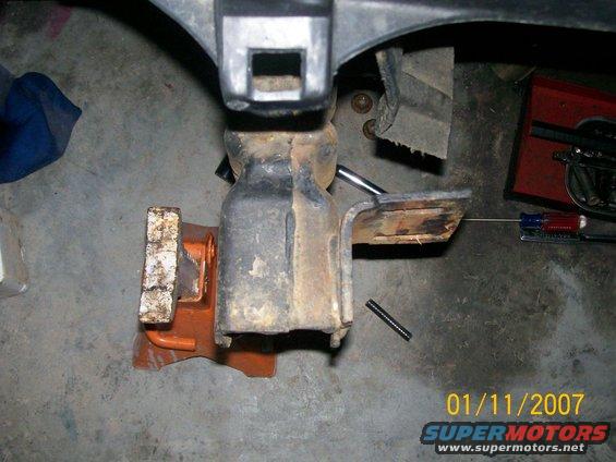 Close-up of a rusty vehicle suspension part held by a jack stand
