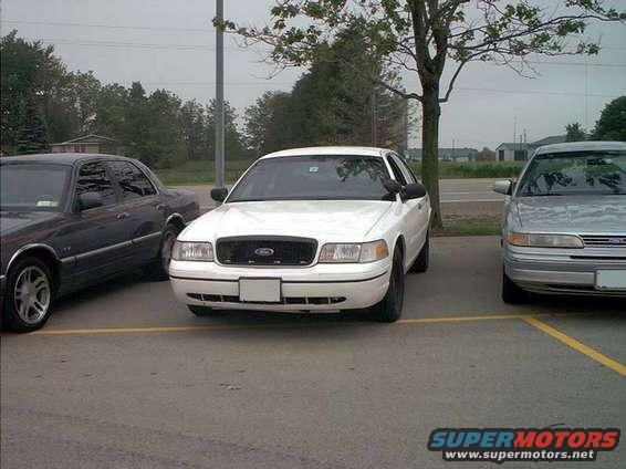 White 2000 Ford Crown Victoria front view parked between two other cars