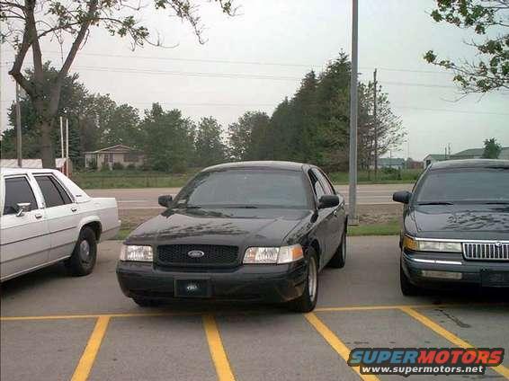 Black 2000 Ford Crown Victoria parked next to a white car and a dark sedan