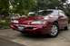 1995 Ford Thunderbird - This red 1995 Ford Thunderbird is parked outside on a paved surface with trees in the background.