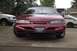 1995 Ford Thunderbird - A red sedan is parked on a driveway, with a white truck visible behind it.