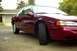 1995 Ford Thunderbird - This red 1995 Ford Thunderbird coupe is shown from a front 3/4 angle, parked in front of a residential garage.