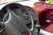 1995 Ford Thunderbird - The interior of a car shows a maroon dashboard and seats, with a black steering wheel and center console.