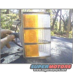 Car turn signal assembly with amber and clear lenses, held by a hand
