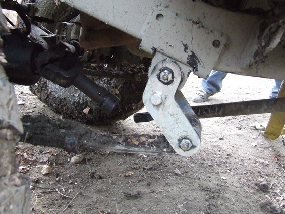 close-up of vehicle's front axle, driveshaft, and suspension linkage