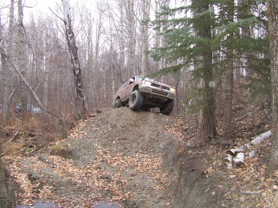 Red 1990 Ford Bronco climbing a dirt hill off-road