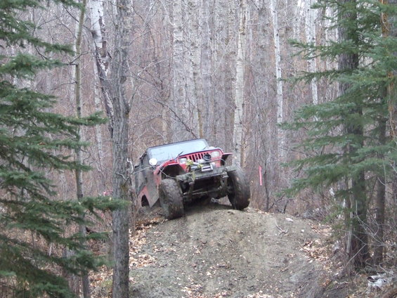 Red off-road vehicle with winch on muddy incline in forest